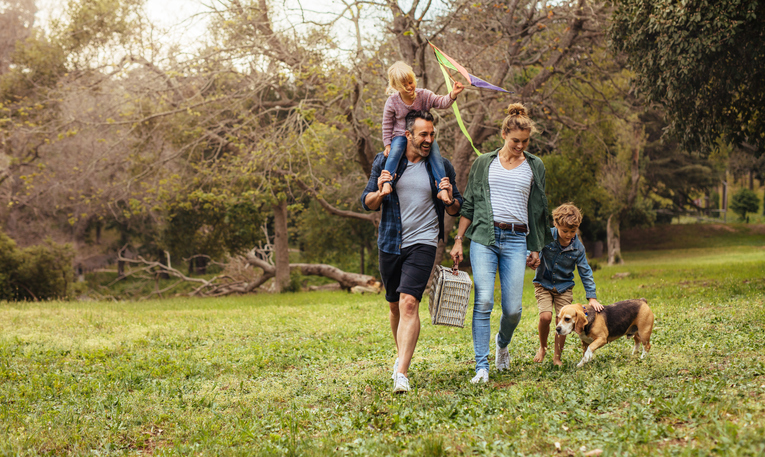 caravan holiday activities family walking with a picnic basket and dog