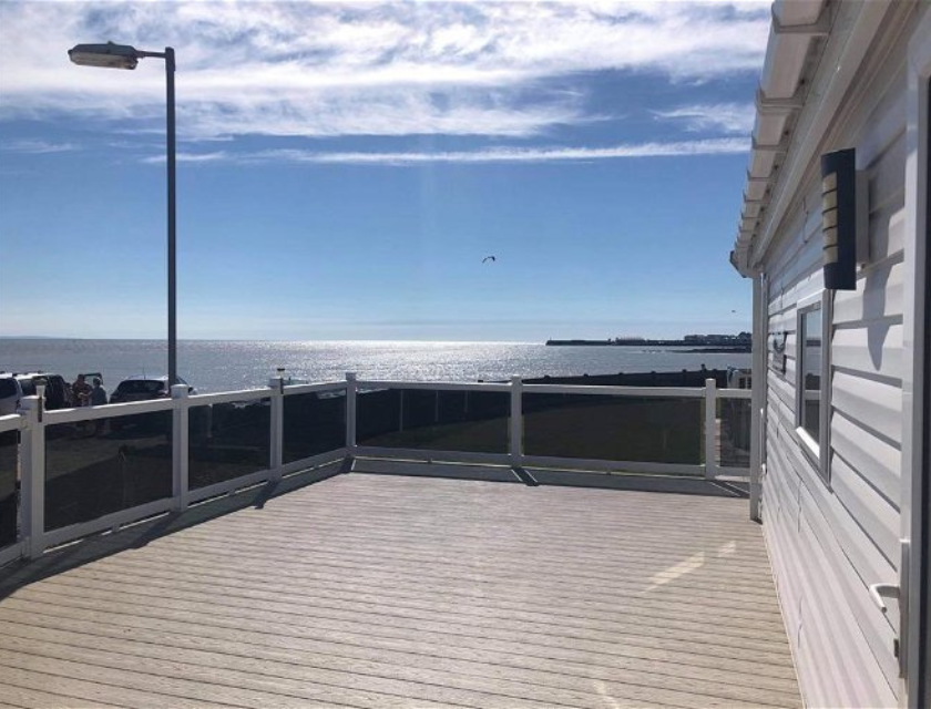 Panoramic view from the deck of a static caravan holiday home at Trecco Bay, overlooking a sunny beach at one of the top caravan holiday parks with indoor pools.