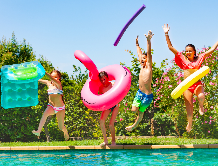 Excited children jumping into an outdoor pool, surrounded by nature